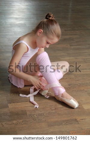 Lovely girl engaged in a pink ballet tutu and pointes in the ballet hall on the wooden dance floor
