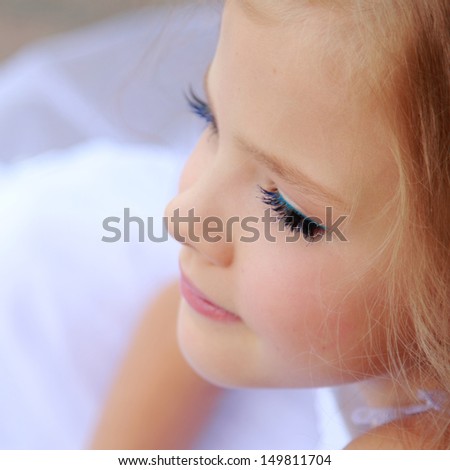 Elegant cute little girl with makeup in a white dress with beautiful hair