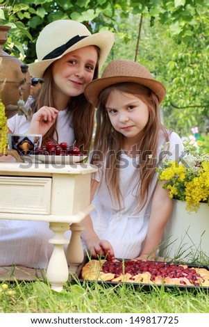 Children drink tea from an old Russian samovar in the garden in the street / Russian national traditions