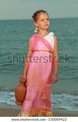 Greek goddess of the tender little dress with a beautiful hairstyle and ornaments sitting on the beach with an amphora/Girl like a goddess
