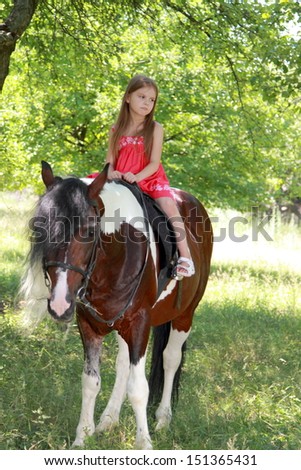 Smiling cheerful child riding a horse at a horse farm
