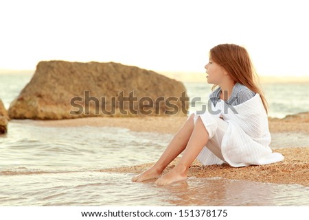 Beautiful girl with long hair and healthy skin on the sea shore and wets feet in water/On the subject of travel and health