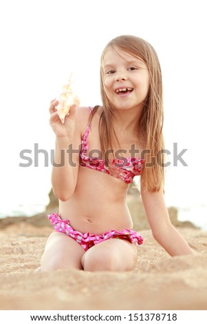 Charming girl in pink swimsuit holding seashell on the Black Sea/Sea theme