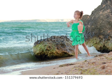 Little girl in a green tunic holds ancient amphora/Little Greek goddess on the beach