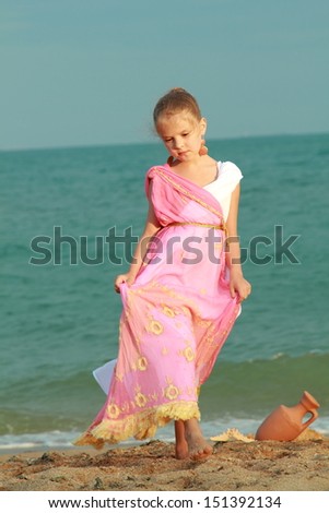 Beautiful elegant girl holding a Greek-style antique amphora and dreams on the beach/Young girl in a role of the Greek goddess of outdoors