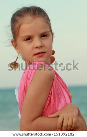 Sweet gentle young girl with a sweet smile and beautiful earrings on a background sea shore