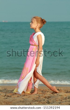 Beautiful elegant girl holding a Greek-style antique amphora and dreams on the beach/Young girl in a role of the Greek goddess of outdoors