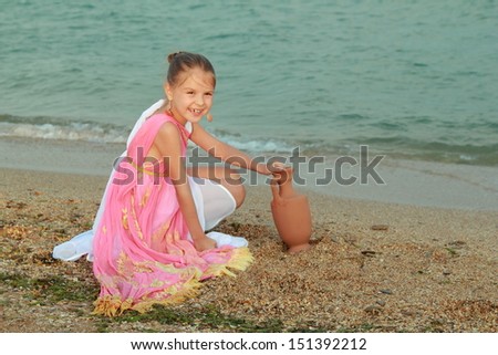 Beautiful little girl in ancient style/Little goddess in a tunic on the beach
