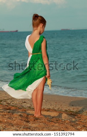 Beautiful little girl in ancient style/Little goddess in a tunic on the beach