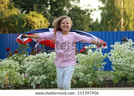 European smiling little girl holding a big UK flag outdoors