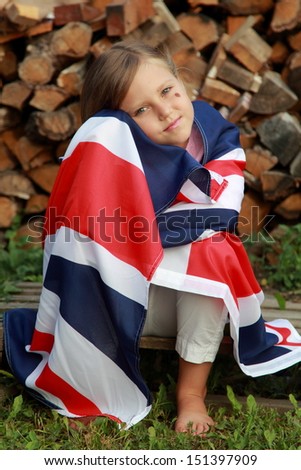 European smiling little girl holding a big UK flag outdoors