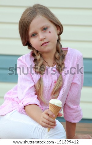 Lovely girl eating ice cream outdoor/Charming child eating ice cream outdoors