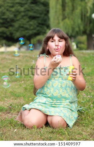 Cute little girl is blowing a soap bubble/Cheerful smiling little girl walks in the park and blows bubbles outside