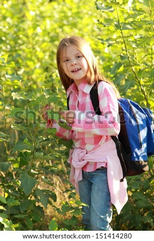 Adorable little schoolgirl with backpack goes to school on Education