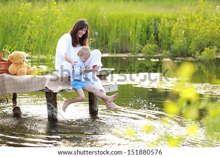 mother with a young son sitting by the lake with her Ã?Â¢??Ã?Â¢??bare feet in the summer