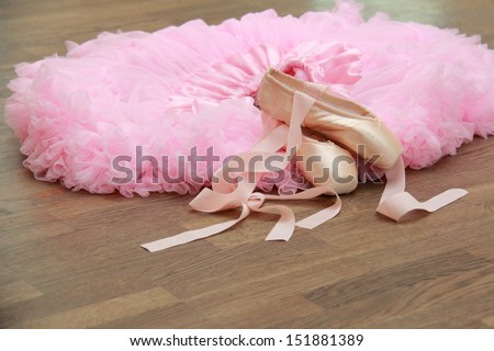 Ballet skirt and ballet shoes for the little ballerina in the background of the old wooden parquet floor