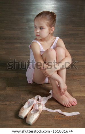 Young ballerina puts on pointe in ballet class at the old wooden dance floor