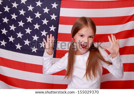 Image of lovely happy smiling little girl on the background of a large U.S. flag/American patriotism