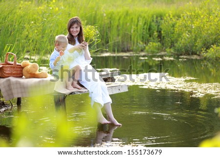 Mom and young son playing at the lake in the Ukrainian countryside/Family idyll mother with her son on a background of green fields and lakes