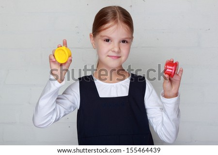 Image of a cute little caucasian girl with a bright smile in school uniform holding paint for painting