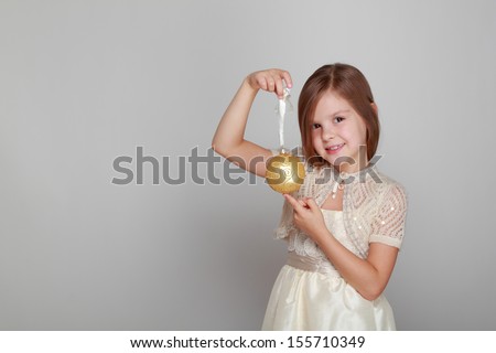 Joyful cute kid with a sweet smile holding a Christmas and New Year decorations on gray background