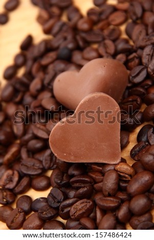 form of heart with lots of coffee beans over light brown wooden background