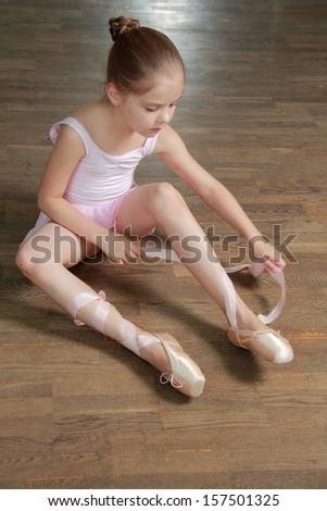 Caucasian ballerina warming up in pointe in the ballet hall on the wooden dance floor