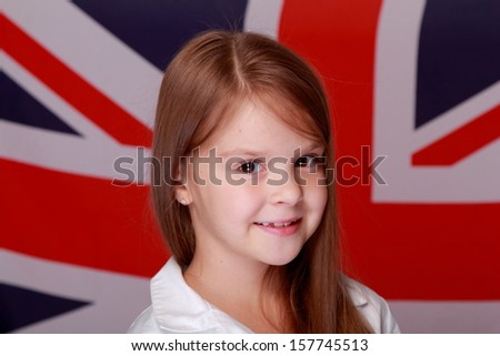 Beautiful little girl with long hair and a sweet smile is on the background of the flag of Great Britain