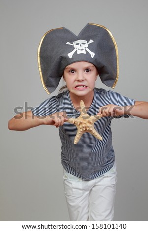 Studio image of a pretty happy girl in a pirate hat holding a starfish