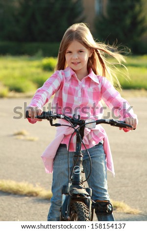 Little girl with her bicycle/Smiling child rides a bicycle outdoors