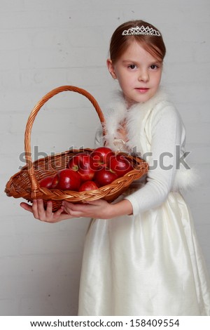Image of a charming healthy girl with a sweet smile, holding a basket with natural red apples on gray background on Food and Drink