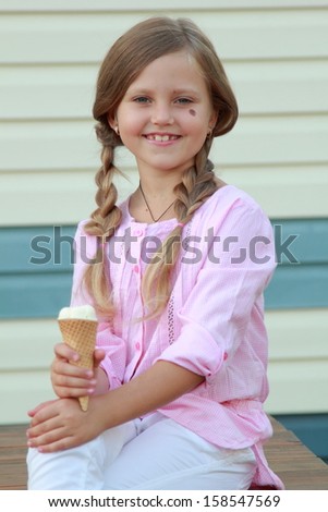 Lovely girl eating ice cream outdoor/Charming child eating ice cream outdoors
