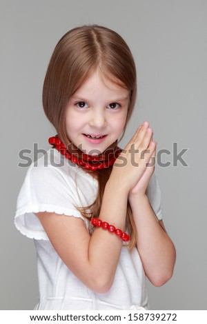 Beautiful girl with red beads on the neck on gray background on Beauty and Fashion