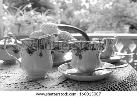 black and white photography image of beautifully laid tables outdoors for tea ceramic tea cups and dessert in the form of a marshmallow