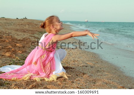 Caucasian sweet young girl in pink tunic in antique style is holding an antique amphora on the sea coast/Greek goddess of beauty