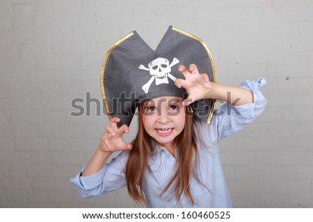 Image of a beautiful young girl in the role of an evil pirate terrible on gray background on Holiday
