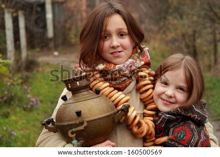 Two cheerful russian young girls with traditional russian food at autumn landscape/Pretty little girls at russian village