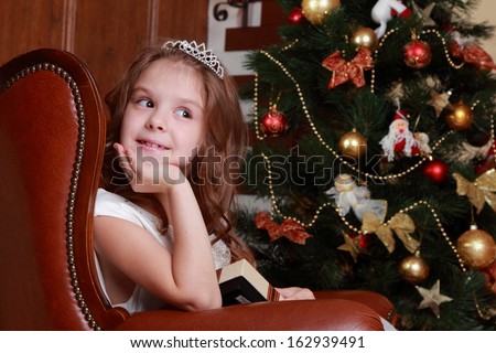 Portrait of beautiful little girl in a dress of Princess around the Christmas tree on Holiday theme/Lovely princess wearing white dress and tiara
