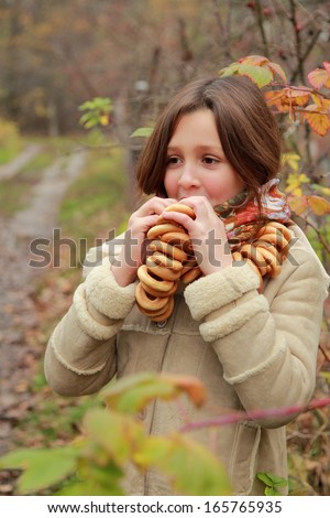Beautiful little girl in russian village traditional kerchief with round cracknel with russian ornamen over autumn weather/Lovely russian young girl with traditional russian food