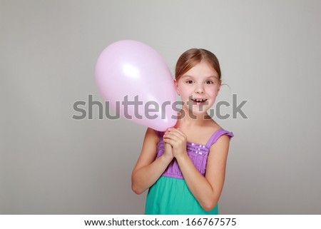 Portrait of lovely cheerful little girl with a sweet smile played with a balloon on gray background/Girl with a pink air balloon on Holiday