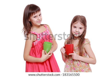Charming smiley little girls with red and green cup
