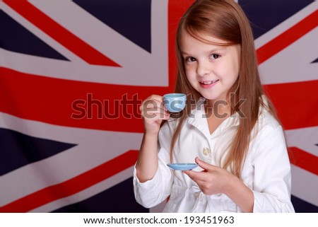 Lovely cheerful young girl holding a cup and saucer for English tea on background of the flag of Great Britain