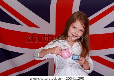 Beautiful happy little girl playing with a cup of tea on a background of the flag UK