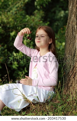 Lovely little girl holding cherries in hand and ready to eat