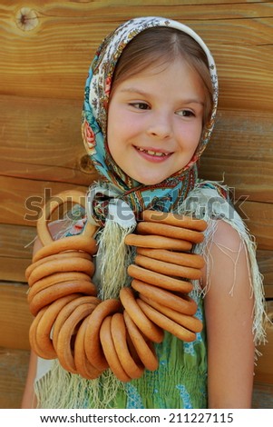 image of beautiful little girl in russian village traditional kerchief with round cracknel with russian ornament over summer weather