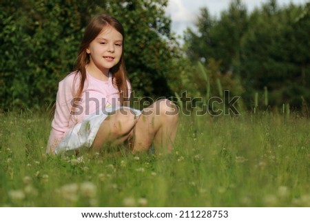 Charming Russian girl sitting in the green grass on a summer day, Russia, Zelenograd