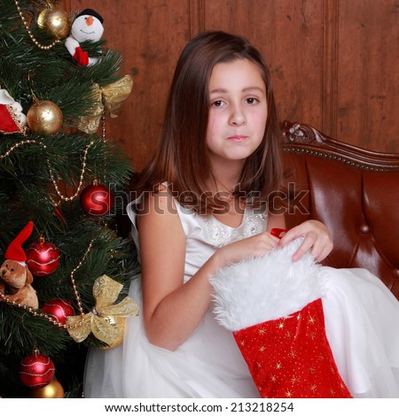 Little girl holding toy near christmas tree/little girl found a christmas present in sock