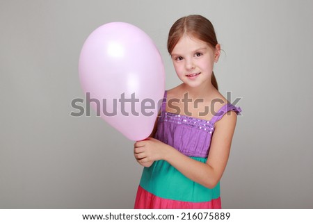 Cute little girl holding balloon on a gray background on Holiday