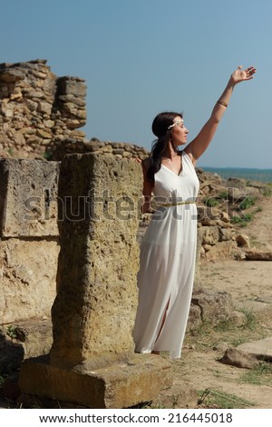 Beautiful girl in a long white wedding dress in Greek style is like the ancient Greek goddess on the excavations on the shores of the Black Sea, Kerch, Crimea