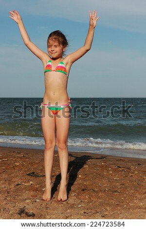 Happy little girl in a swimsuit is played on sand near the Black  Sea and relaxing, East Crimea, Russia
